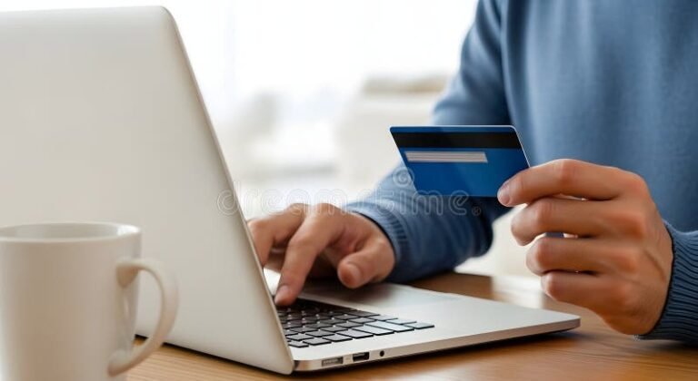 henkilo kirjoittaa tietokonetta ja pankkikortti vieressa