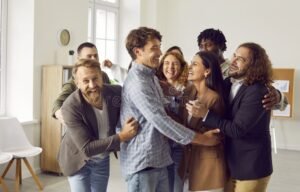 hymyilevat kollegat seisovat yhdessa juhlatilassa