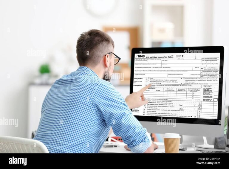 ihminen kayttaa kannettavaa tietokonetta verolaskuri edessa