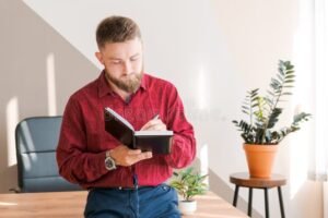 ihminen kirjoittaa budjettimuistikirjaan poydan aaressa