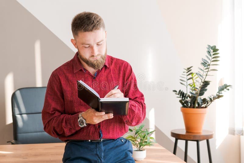 ihminen kirjoittaa budjettimuistikirjaan poydan aaressa