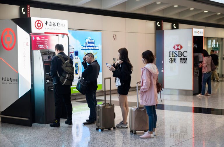 kansainvaliset matkailijat kayttamassa pankkiautomaattia