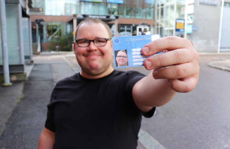 Tarvitseeko Kela-korttia saadaksesi Kelan etuuksia 6 kela kortti kadessa hymytteleva henkilo