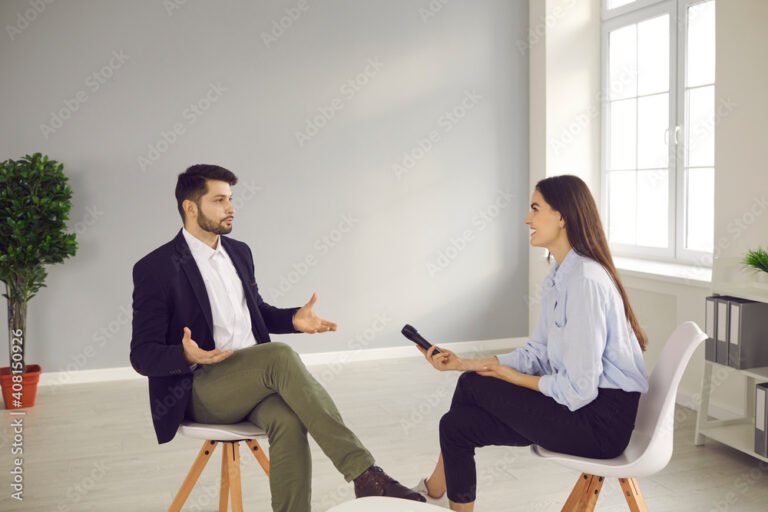 nuori hymyileva haastattelija ja haastateltava keskustelussa